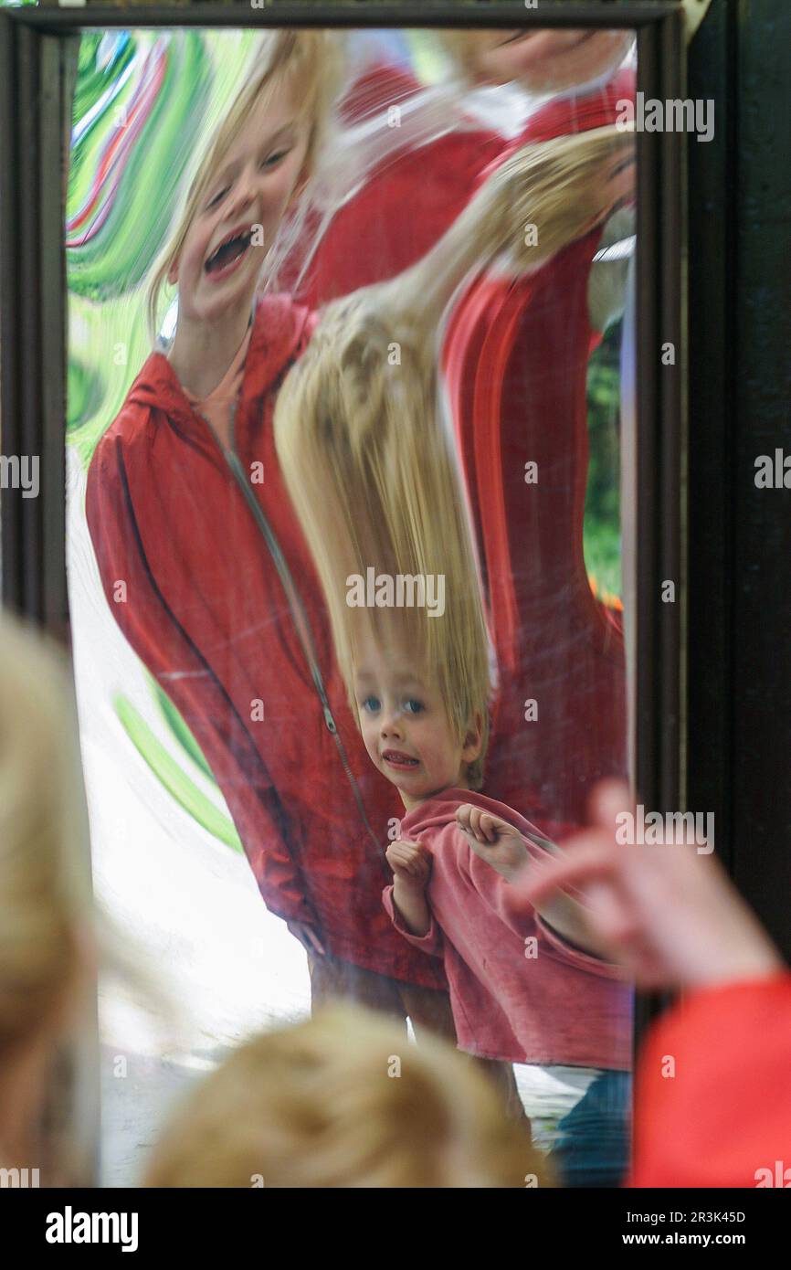 Netherlands, children look in a distorting or carnaval mirror. Stock Photo