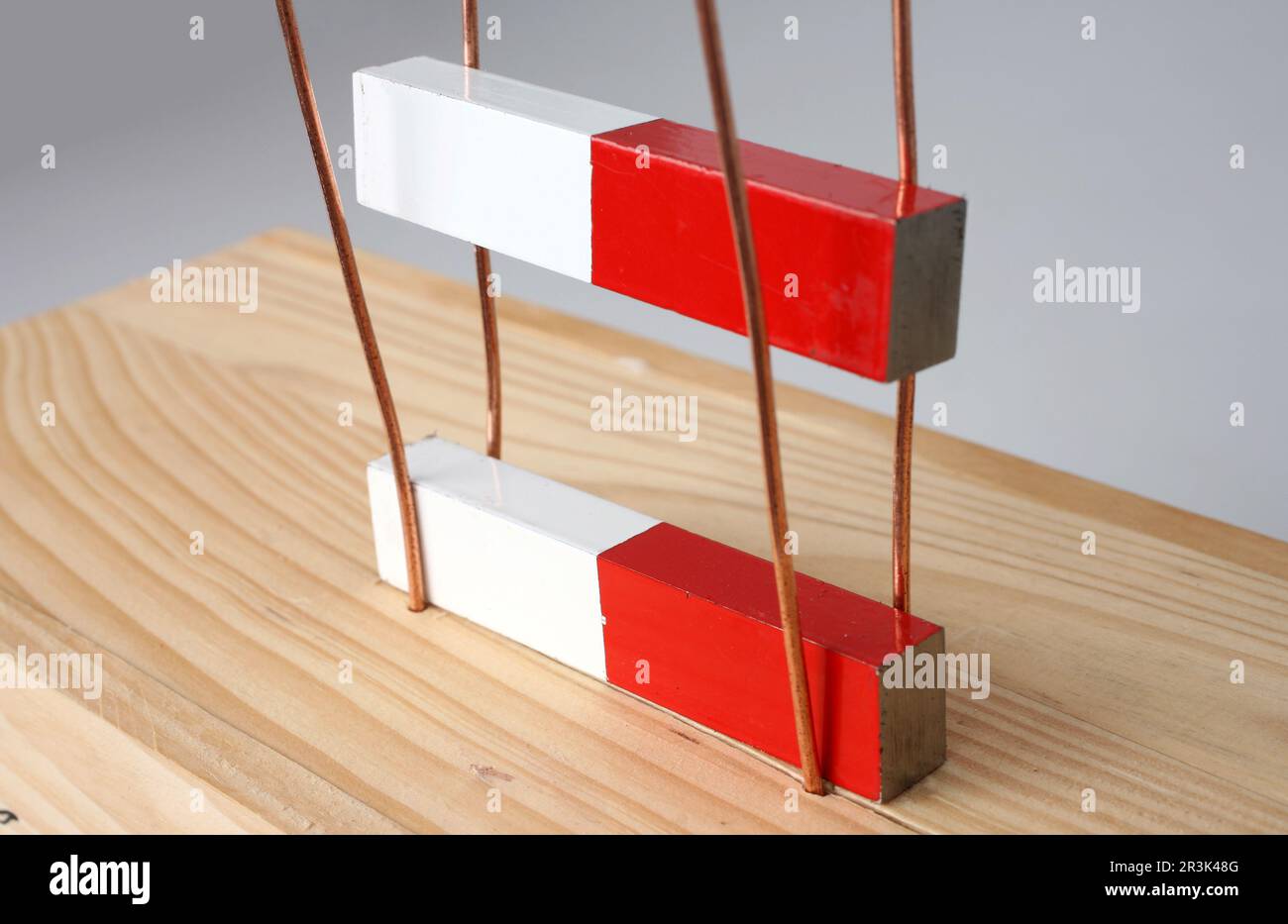 Close-up of two magnets repelling each other. One floats above the other because they are held back by rods. Stock Photo