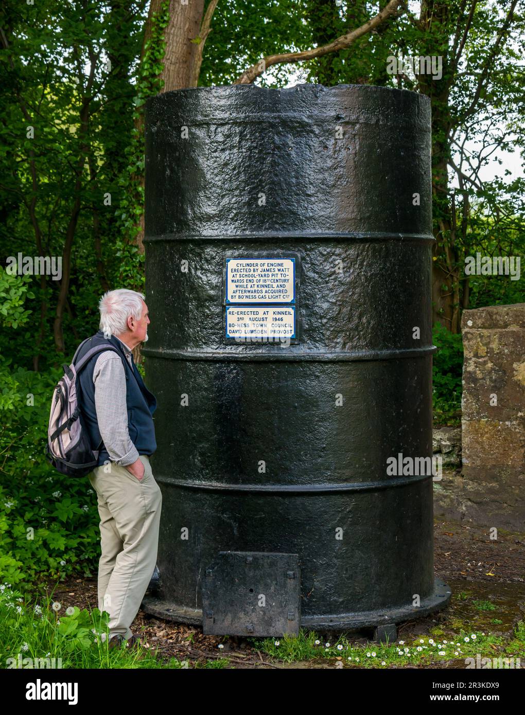 Older man looking at information on James Watt engine cylinder displayed at Kinneil, Bo'Ness, Scotland, UK Stock Photo