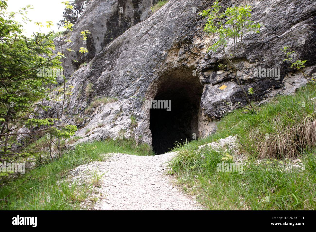 Footpath leading to entrance to the cave in Jura mountains. Black hollow in rock. Mountain tunnel hiking trail, cave enter of dark corridor, Gorges de Stock Photo