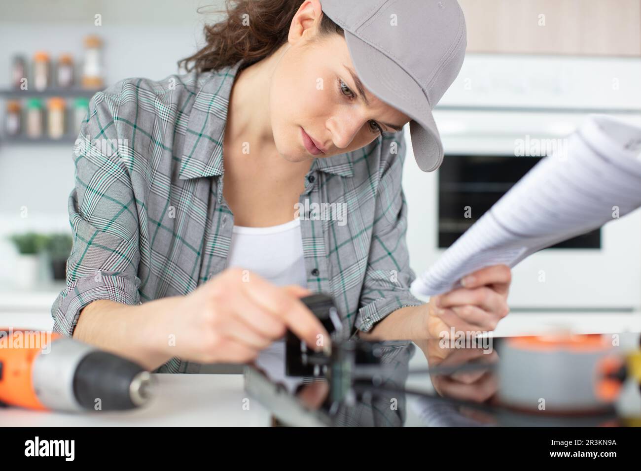 woman installing induction hobs in a kitchen Stock Photo