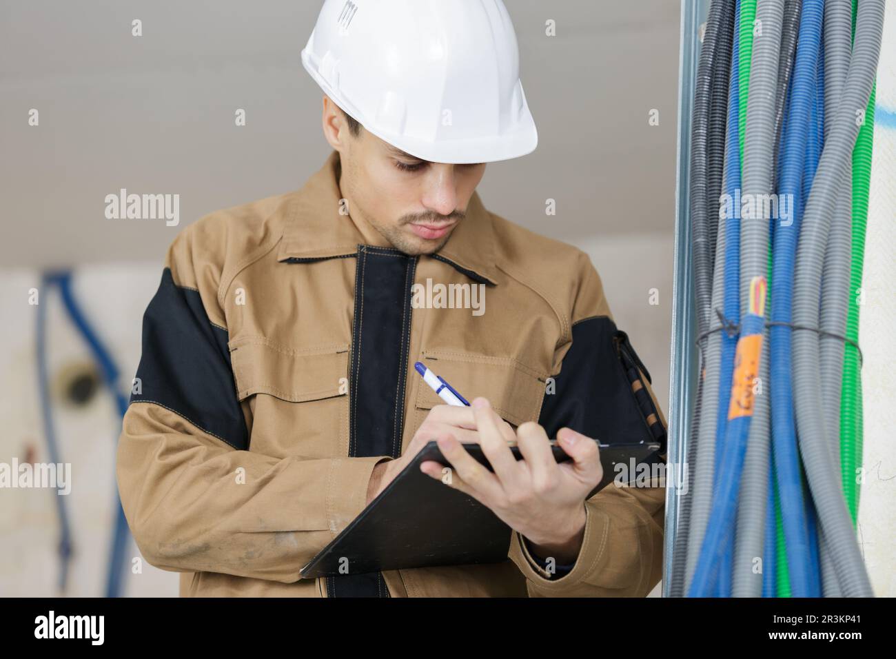 young male contractor making notes on clipboard Stock Photo