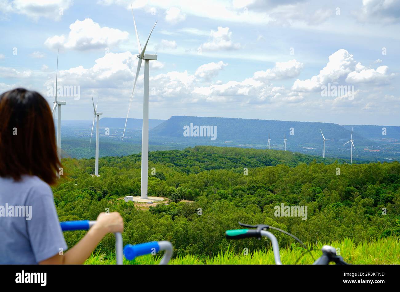 Wind farm with woman riding bike in foreground. Wind energy. Wind power