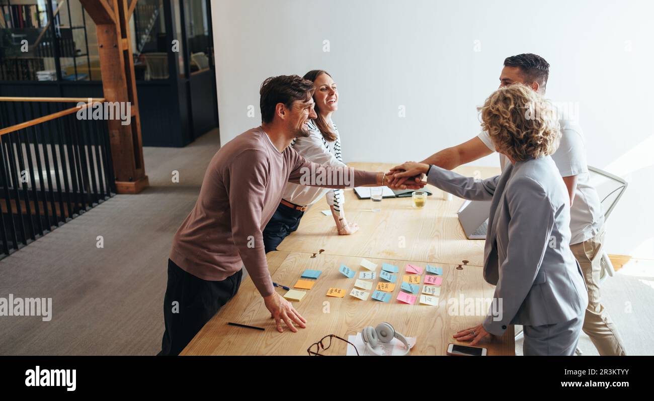 Professionals stacking hands together during a meeting in an office. Creative business people working together on a project. Teamwork and collaboratio Stock Photo