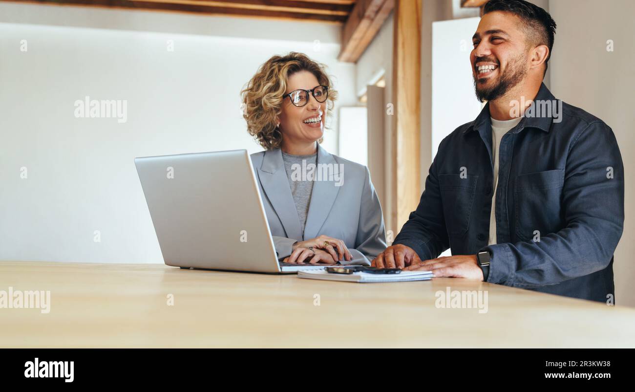 Happy business colleagues working together in an office. Two business people having a meeting about a project. Teamwork and collaboration between busi Stock Photo