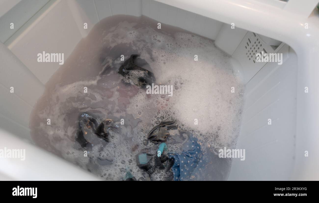 Dirty clothes in top loading washing machine. Clothes with bubble of laundry detergent in