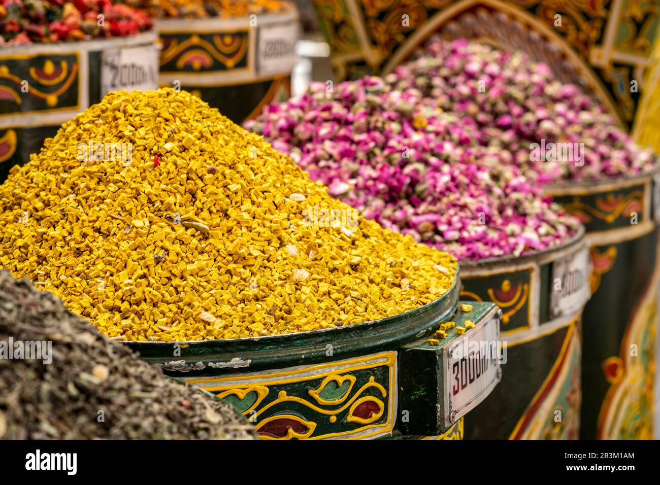 Heaped metal cans filled with colourful dried flowerheads and other herbs outside a herbal remedy souk in Marrakesh Medina, Morocco. Stock Photo