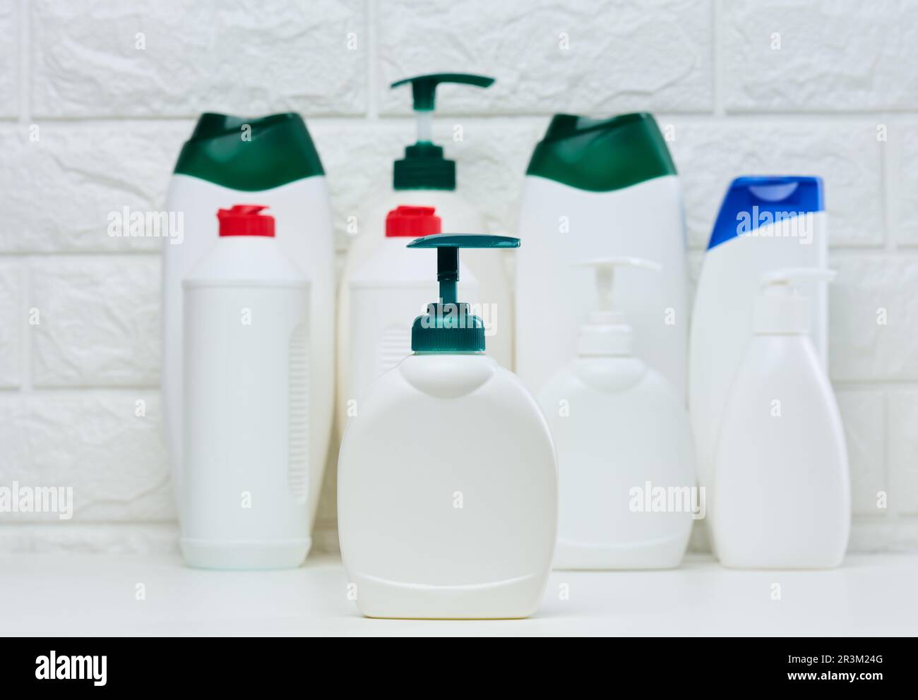 White plastic container with a pump for liquid products on a white shelf. Container for cosmetics Stock Photo