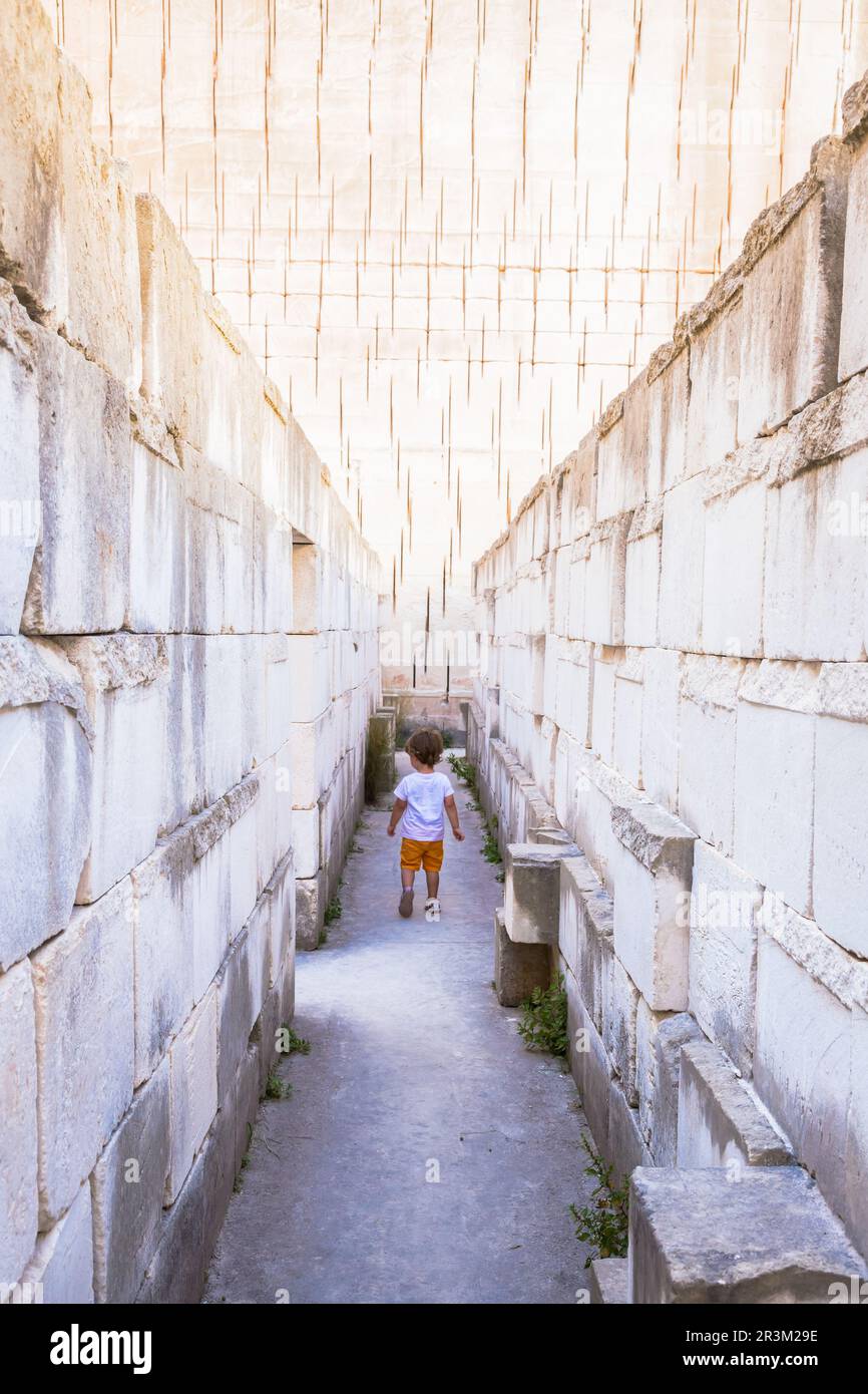 Caucasian young kid walking in a labyrinth. Conceptual image for dangerous situation during childhood. Stock Photo