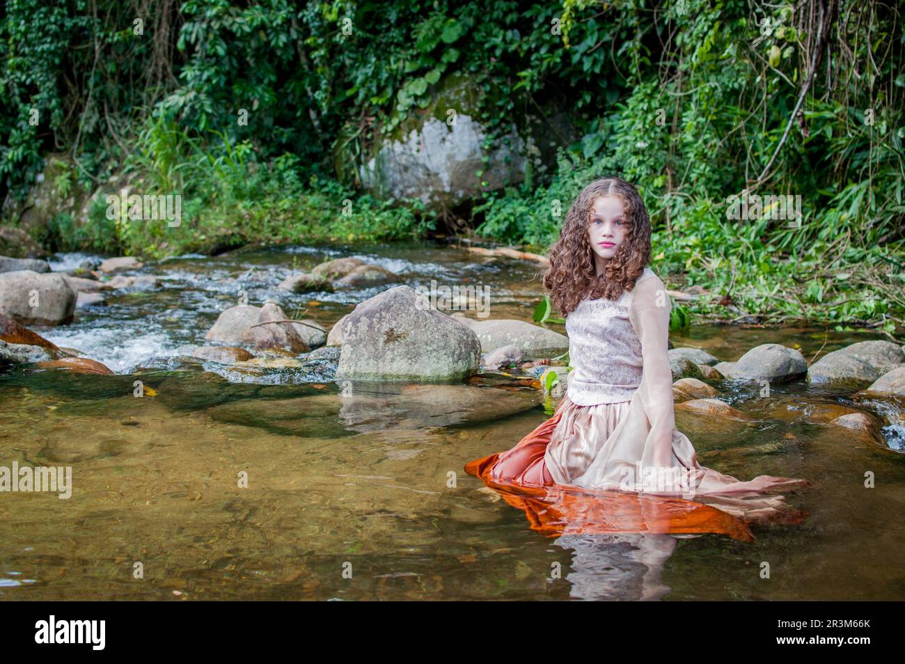 Portrait of a beautiful girl posing inside the river wearing a princess ...
