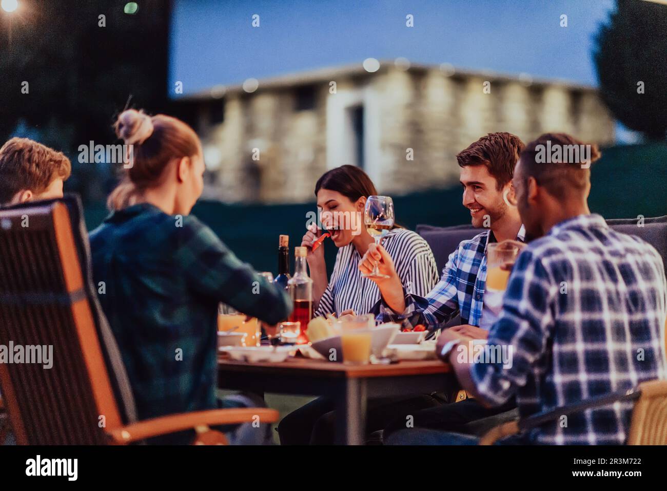 A group of young diverse people having dinner on the terrace of a
