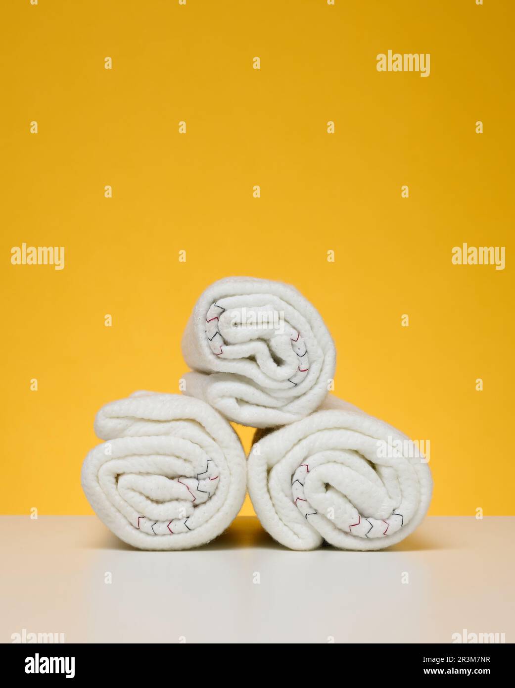 Twisted white rags for mopping on a yellow background Stock Photo