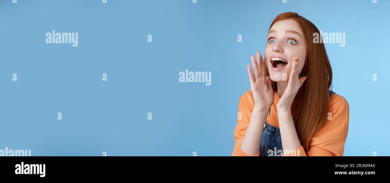 Attractive silly european redhead young girl 20s calling friend searching someone crowd look relaxed joyfully yelling hold hands Stock Photo