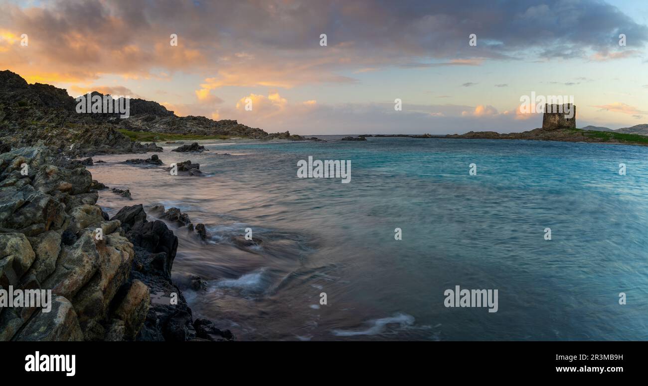 Panorama landscape with rocky shore at sunset and the Torrre de la Pelosa watchtower in northern Sardinia Stock Photo