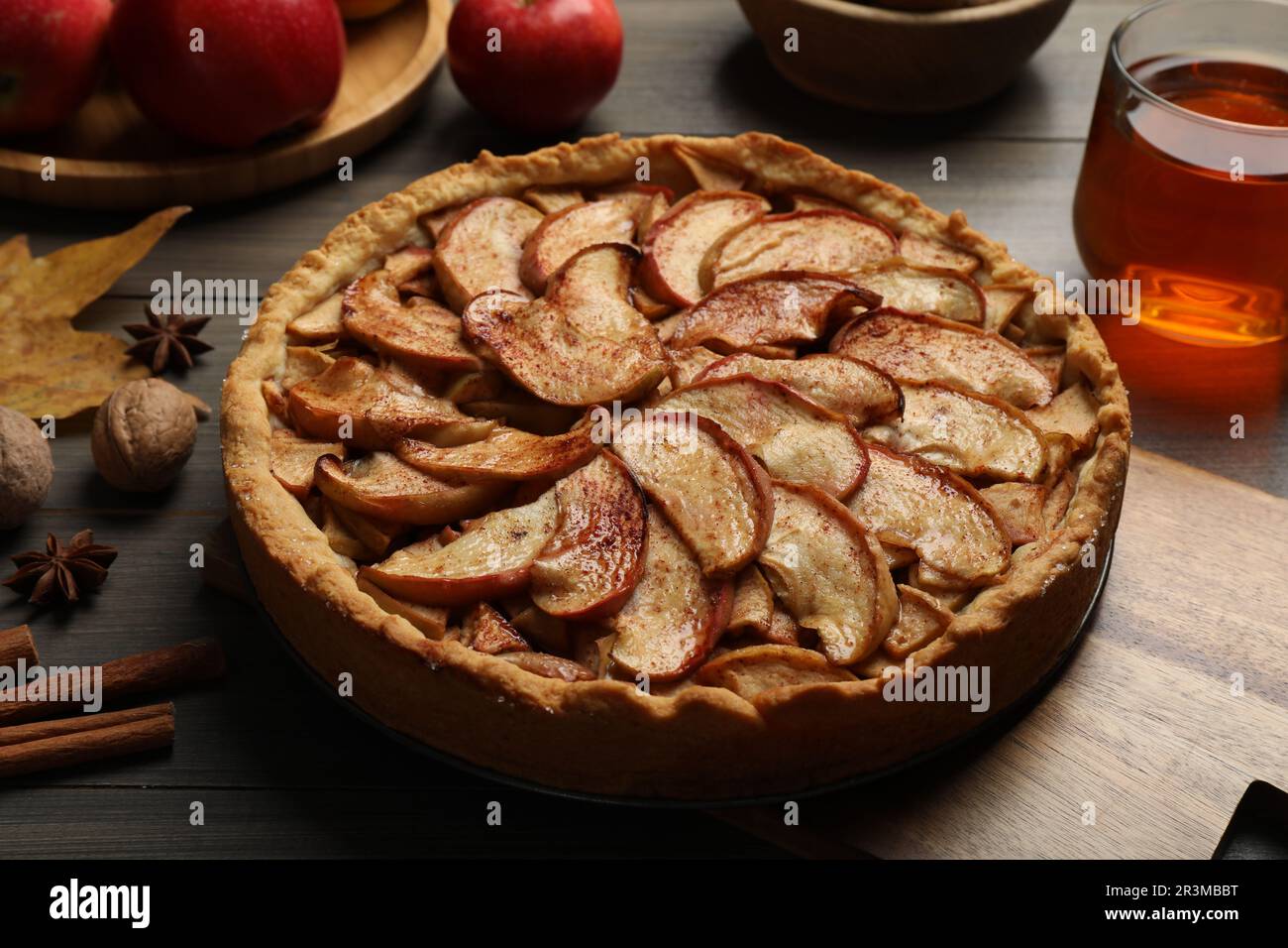 Delicious apple pie, ingredients and cup of tea on wooden table Stock Photo