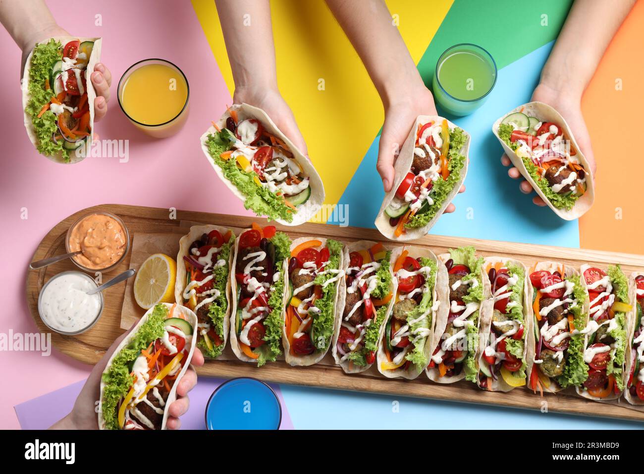 Friends holding delicious tacos on color background, top view Stock Photo