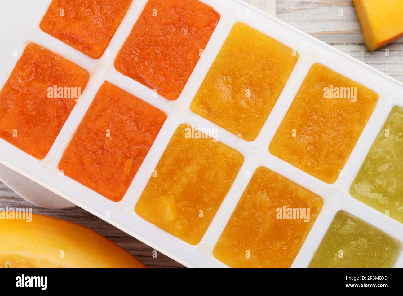 Different puree in ice cube tray on table, top view. Ready for freezing