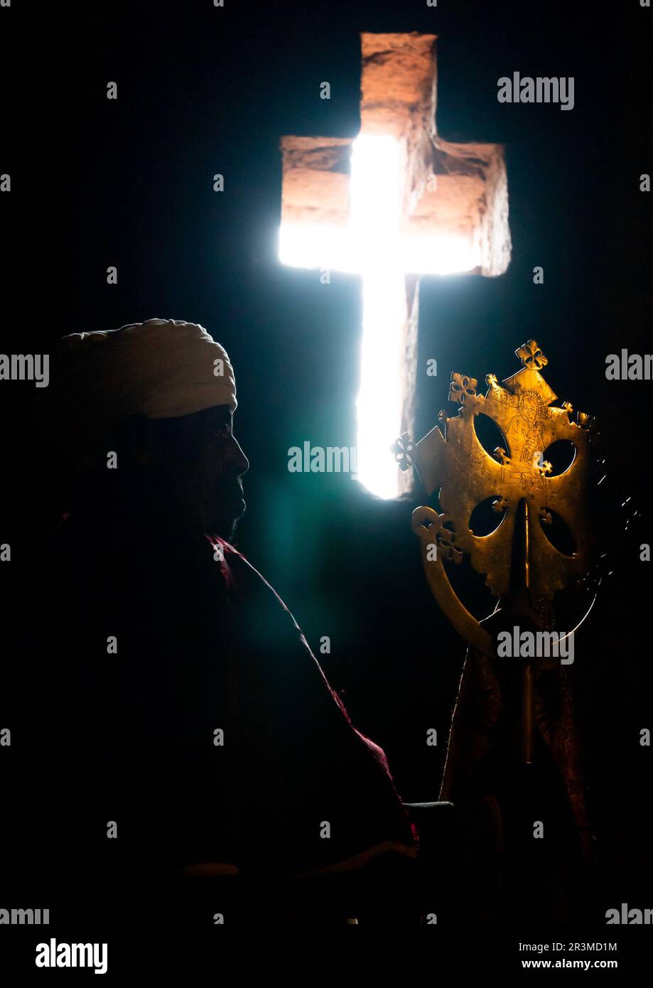 Ethiopian orthodox priest holding a cross inside a rockhewn church