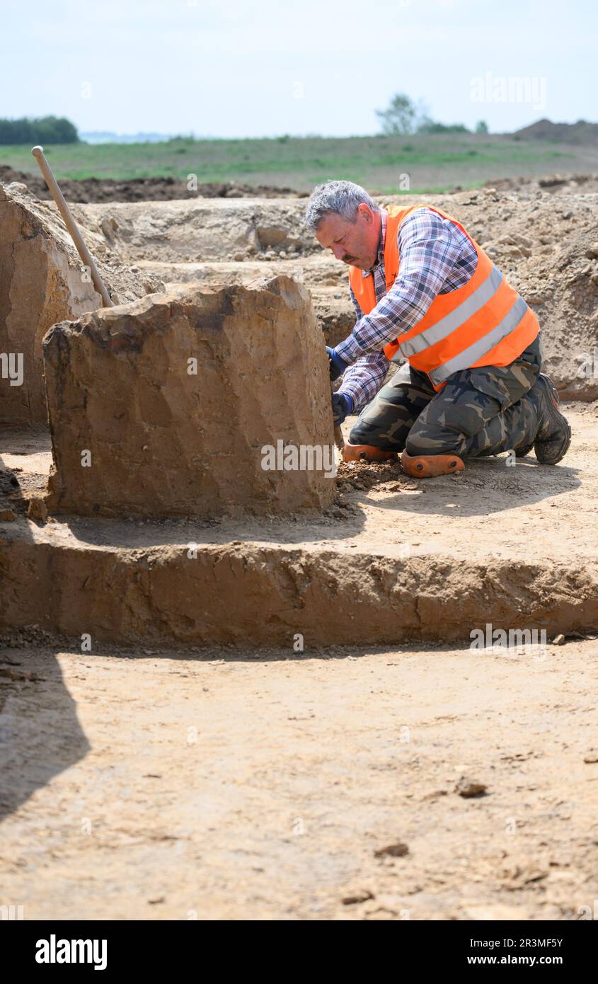 24 May 2023, Saxony, Döbeln: An employee of the Saxony State Office for Archaeology works during excavations on the construction site of the future 'Karls Erlebnisdorf'. Since fall 2021, the Saxony State Office for Archaeology has been conducting extensive excavations on the 17-hectare site of the future adventure village near Döbeln. With its wealth of finds and immense size, the site near Döbeln-Gärtitz is one of the largest settlement sites of the Early Neolithic period (5,500 - 4,500 BC) in the Middle Saxon loess region known to date. Photo: Robert Michael/dpa Stock Photo