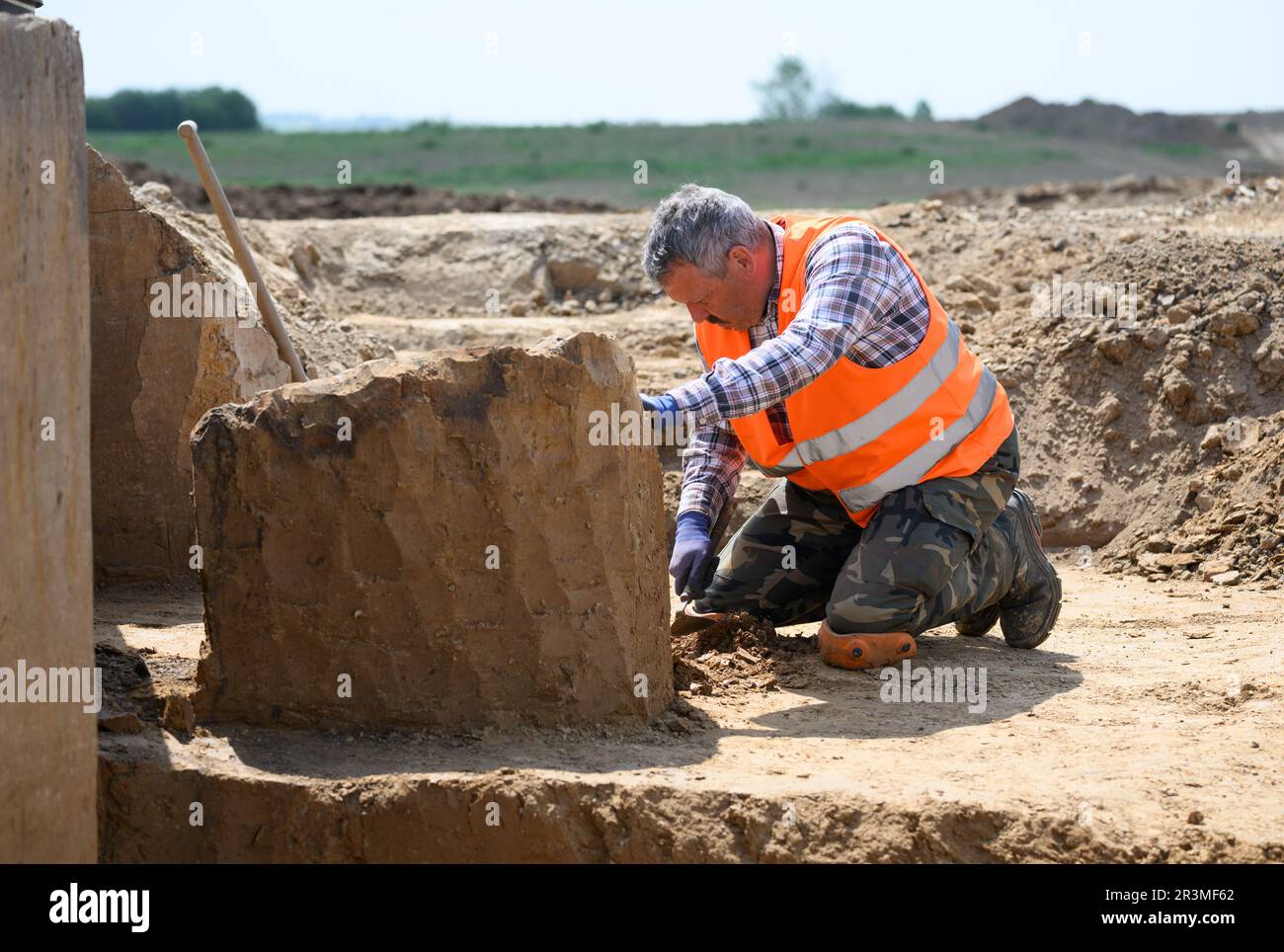 24 May 2023, Saxony, Döbeln: An employee of the Saxony State Office for Archaeology works during excavations on the construction site of the future 'Karls Erlebnisdorf'. Since fall 2021, the Saxony State Office for Archaeology has been conducting extensive excavations on the 17-hectare site of the future adventure village near Döbeln. With its wealth of finds and immense size, the site near Döbeln-Gärtitz is one of the largest settlement sites of the Early Neolithic period (5,500 - 4,500 BC) in the Middle Saxon loess region known to date. Photo: Robert Michael/dpa Stock Photo