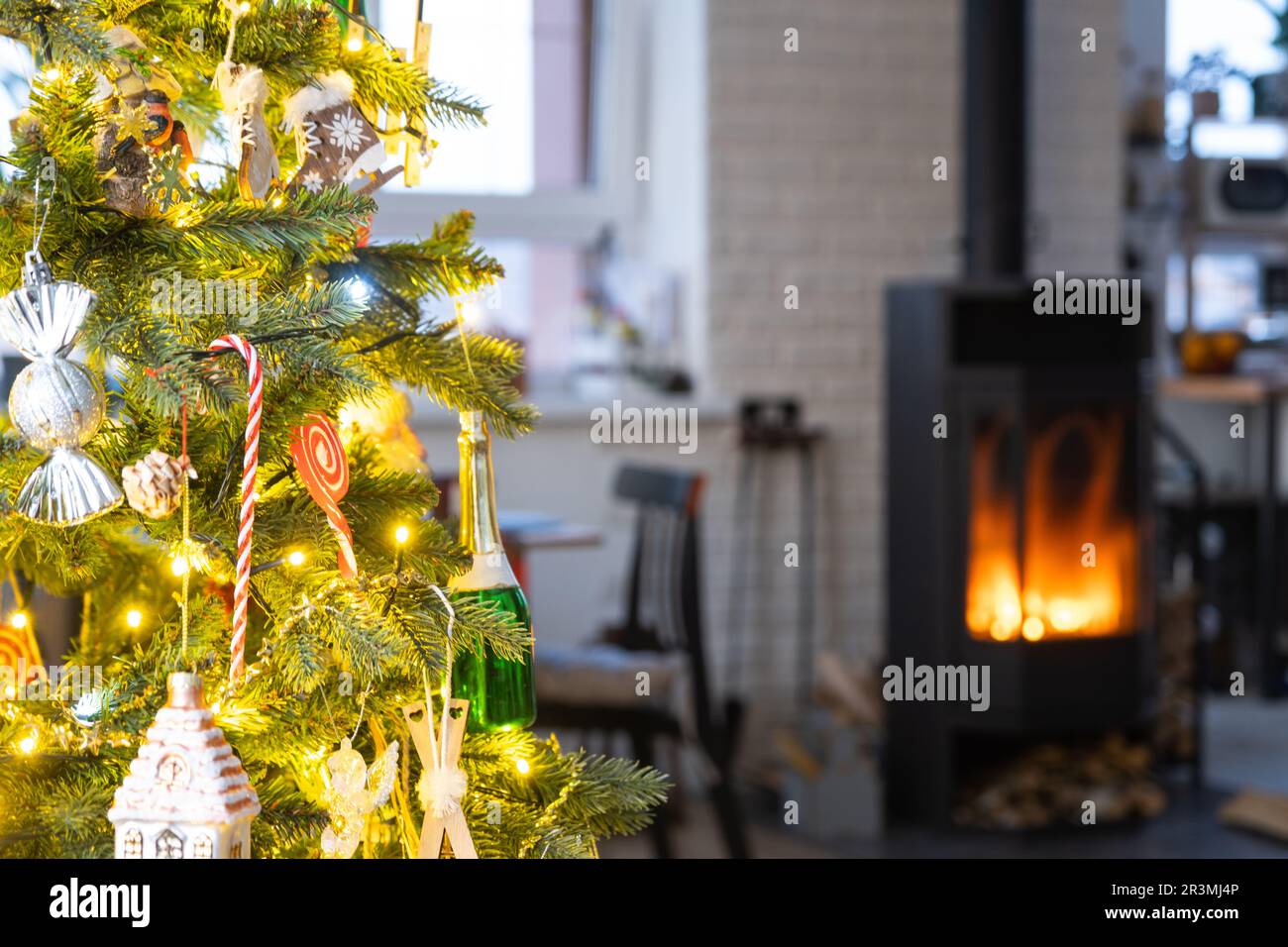 Festive interior of house is decorated for Christmas and New Year in loft style with black stove, fireplace, Christmas tree. War Stock Photo