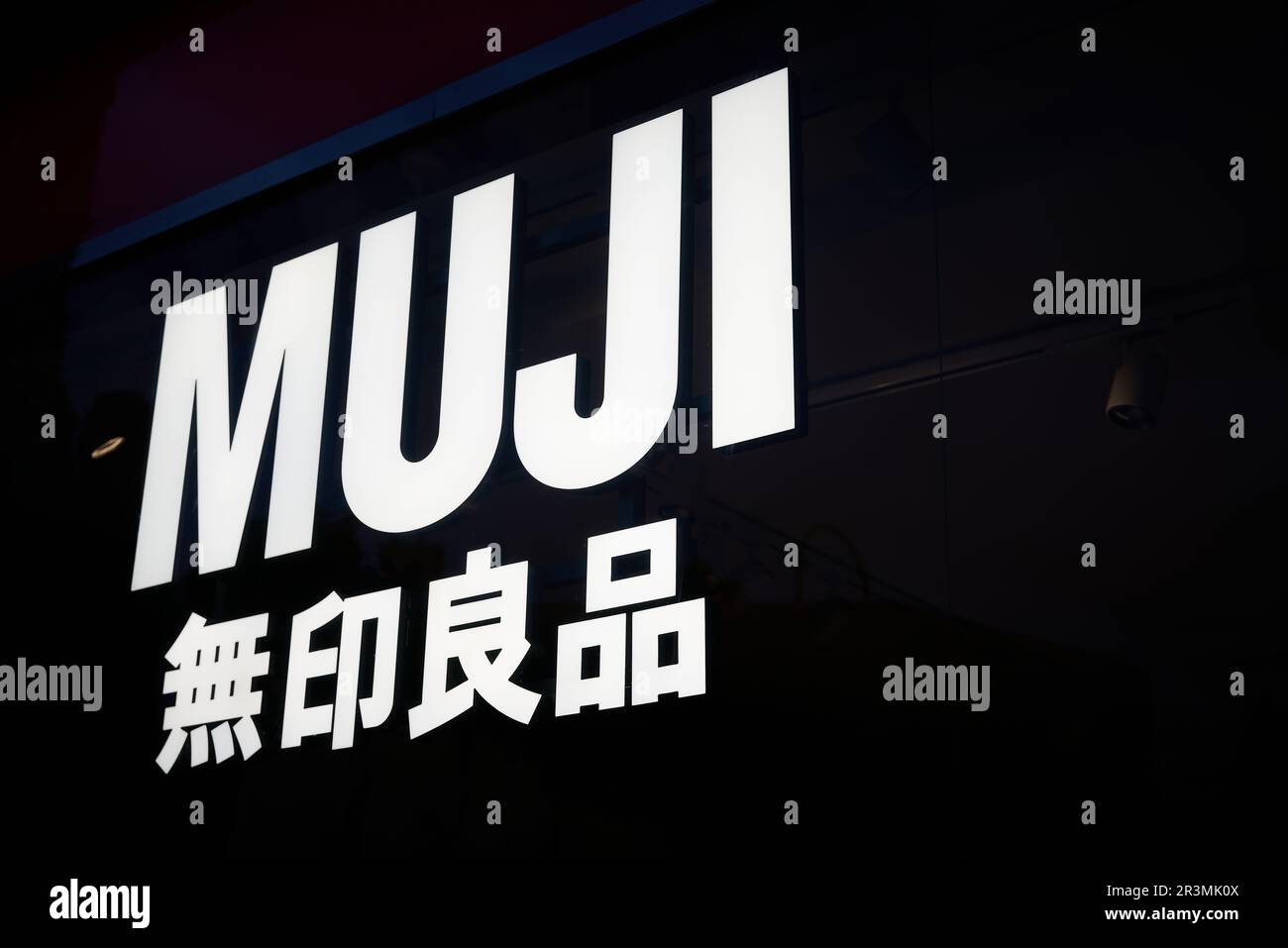 Illuminated sign of the Japanese unbranded lifestyle chain MUJI at a store in downtown Berlin Stock Photo