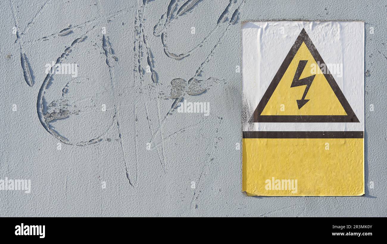 Old danger sign with indication of high voltage on a door to an industrial building Stock Photo