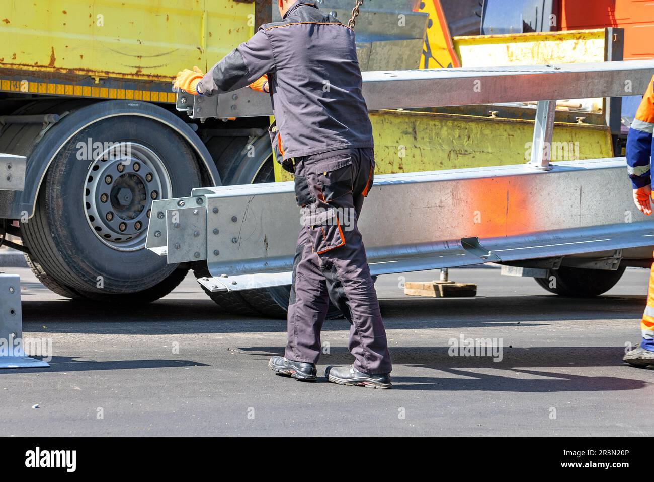A road service worker installs a delimiting metal barrier in the middle of the carriageway. Stock Photo
