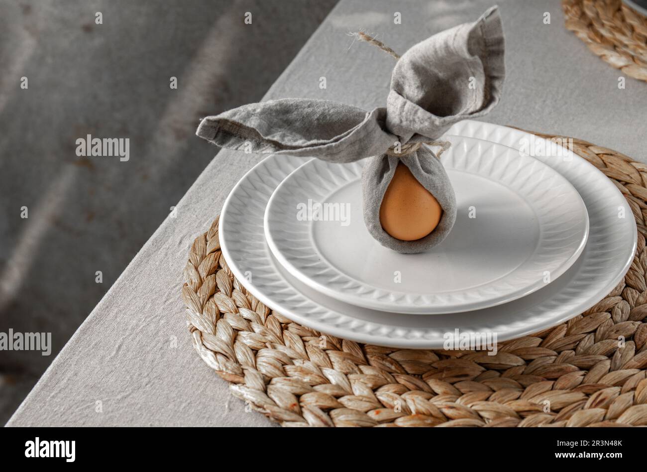 Festive Easter table setting. Funny Easter bunny made of egg and linen napkin on plate. Gray background Stock Photo