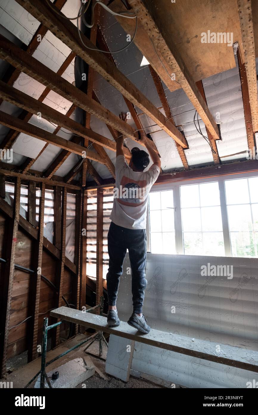 Construction worker installing loft insulation boards into an attic of ...