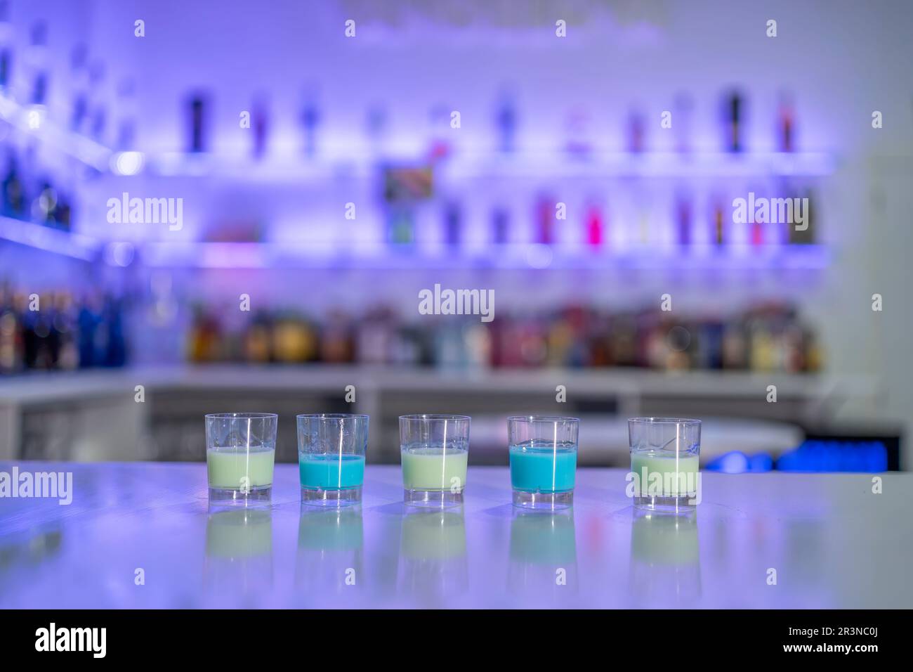 Row of served shots with blue and white liquors placed in row on