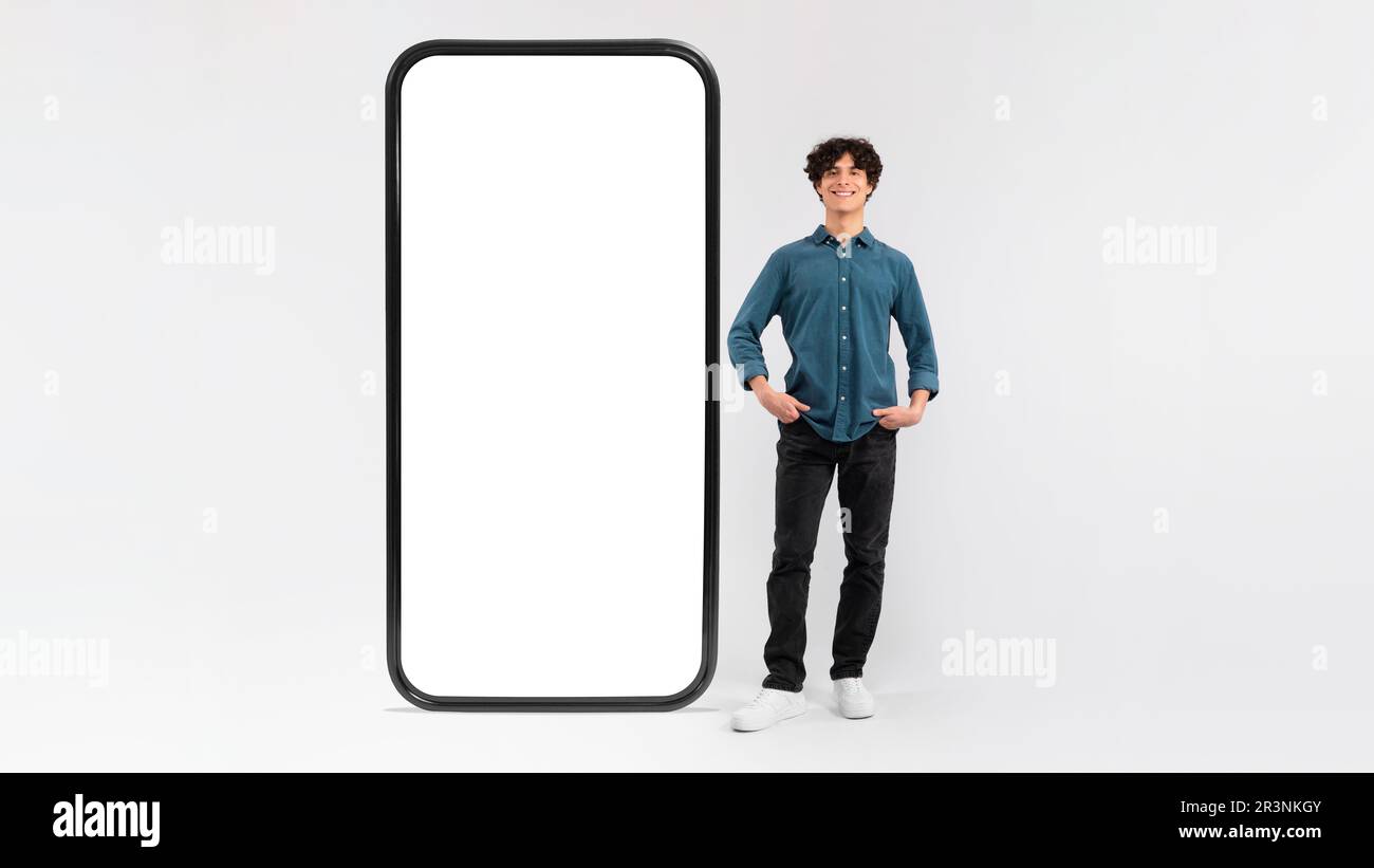 Man Standing Near Huge Cellphone Empty Screen On White Background Stock Photo