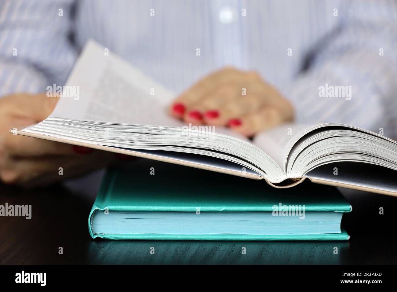 Woman reading a book while sitting at table. Concept of education and literature Stock Photo