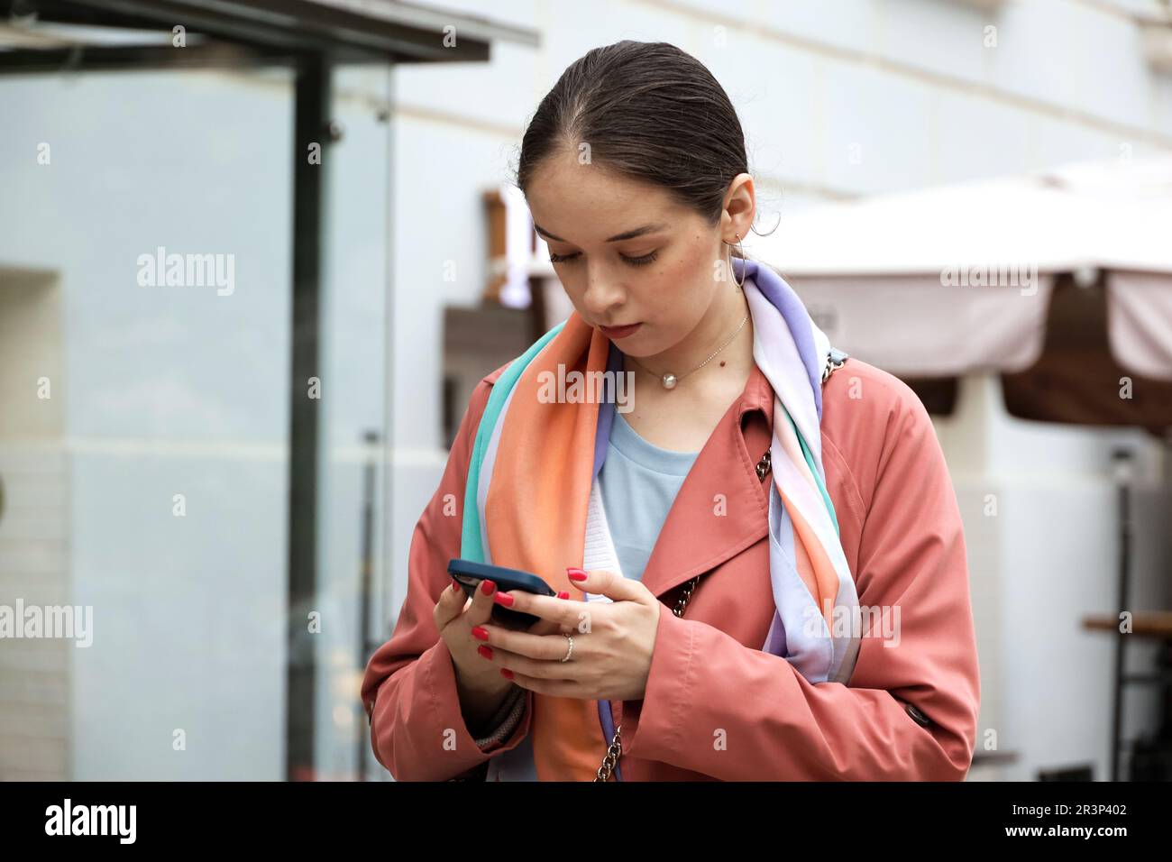 Girl standing with smartphone on a street. Using mobile phone in city Stock Photo
