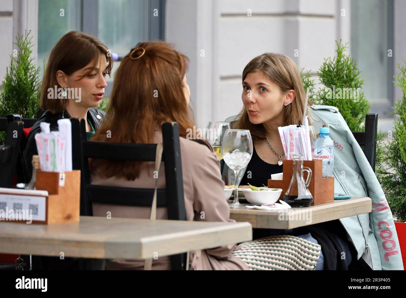 Three women eating and talking while sitting on terrace of street cafe. Life and leisure in city Stock Photo