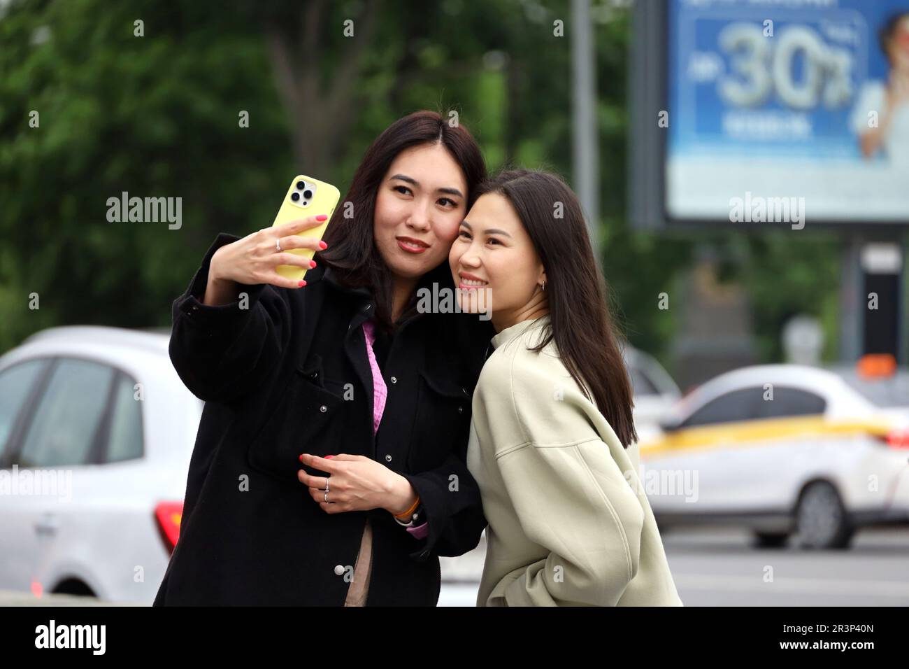 Asian girls taking selfie on smartphone camera while walking on city street Stock Photo