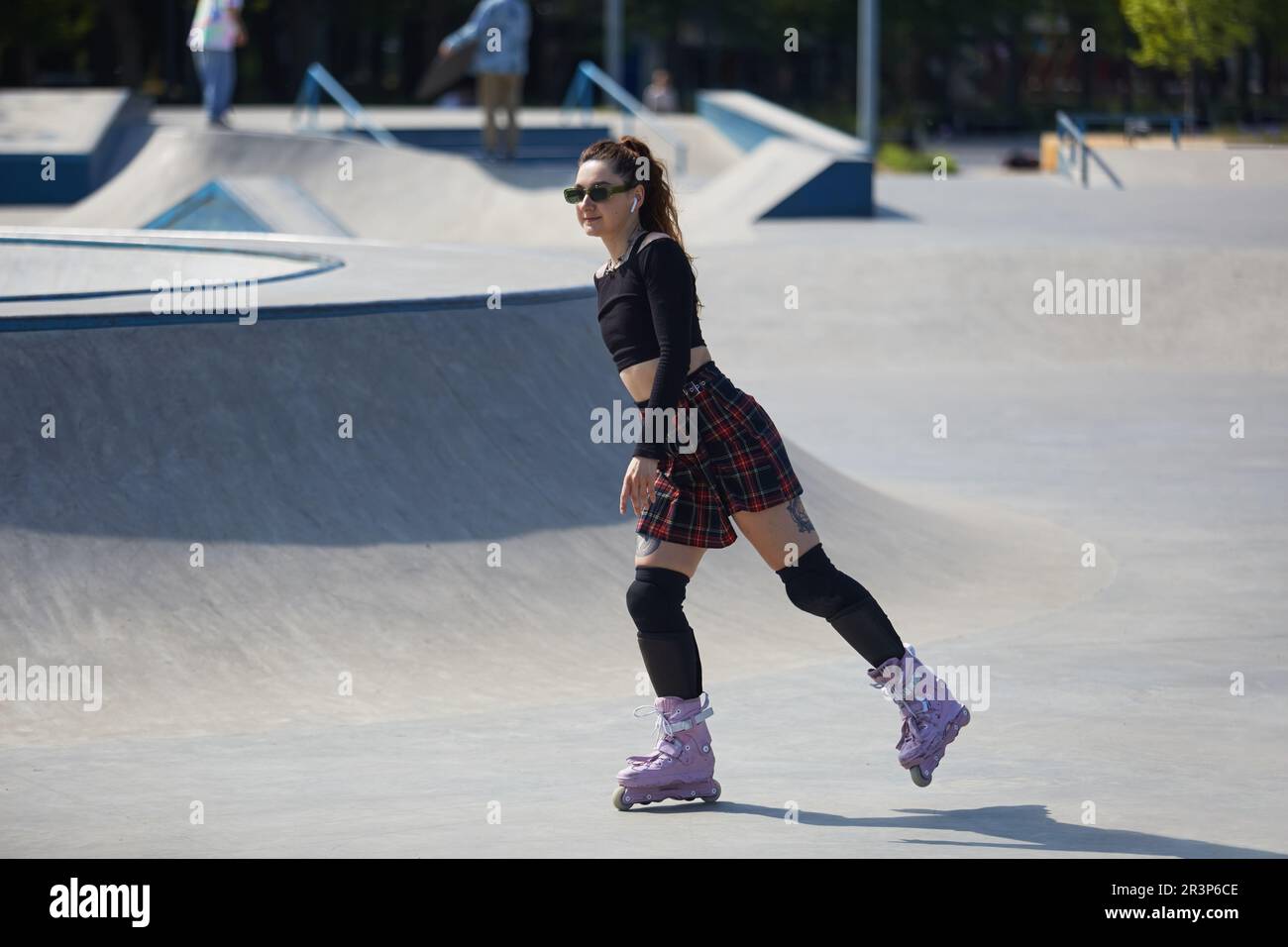 Cute young adult female riding on aggressive inline skates in a