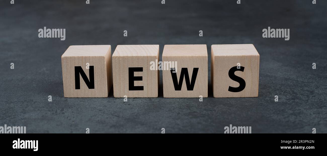 The word news is standing on wooden blocks, social media, newspaper and TV Stock Photo