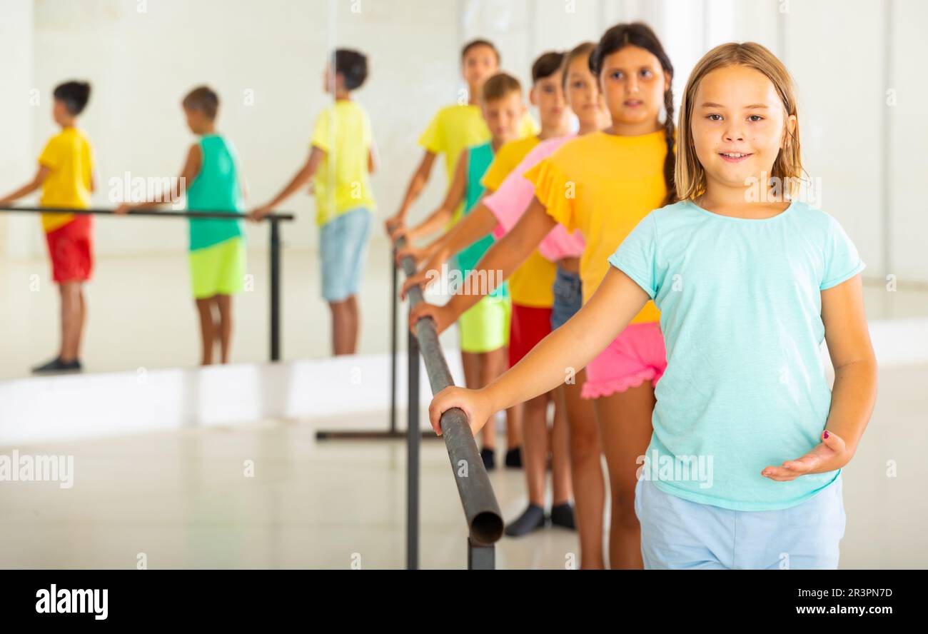 Children standing along ballet bar in dance studio during dance class Stock Photo