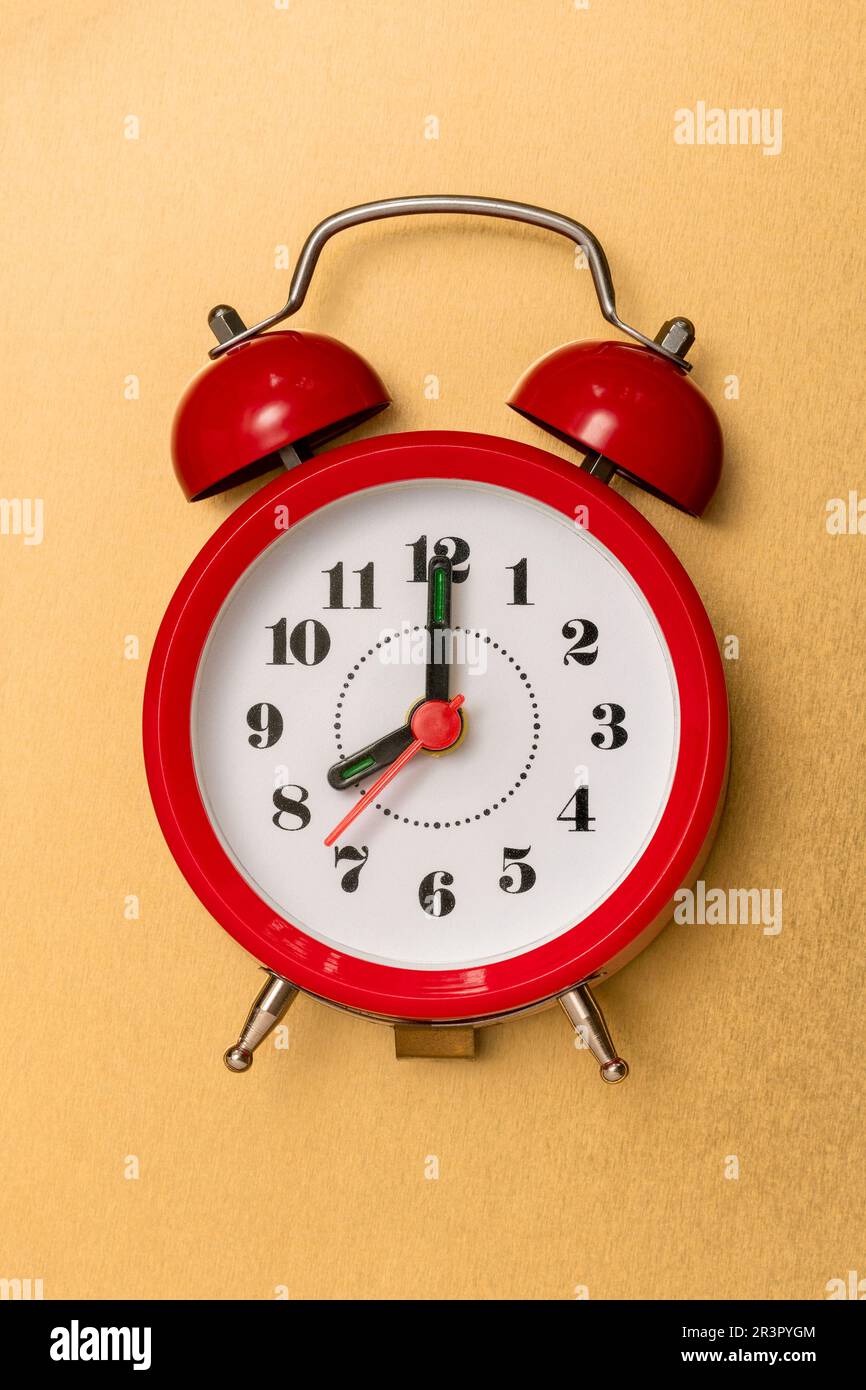 Red alarm clock lying on the golden background Stock Photo