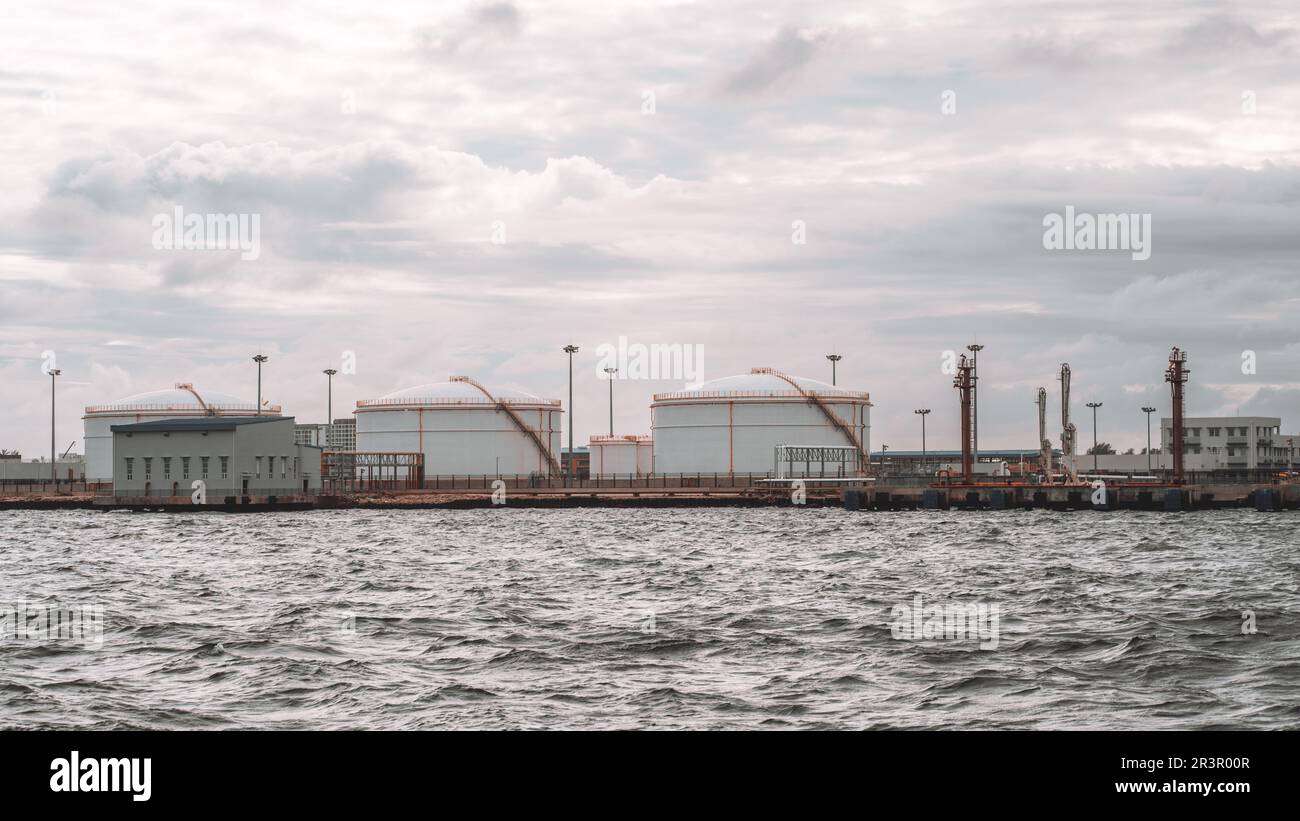 Grey sea waters stretch in the foreground, with aviation fuel storage tanks at Male's airport in the background, showcasing the vital infrastructure o Stock Photo