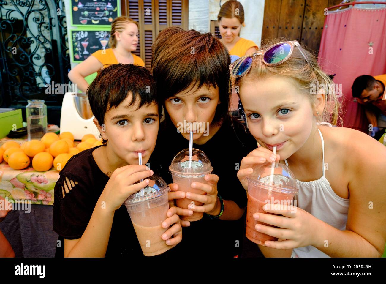 tres niños bebiendo batido de frutas, mercado comarcal, Santanyi, Mallorca, balearic islands, spain, europe. Stock Photo