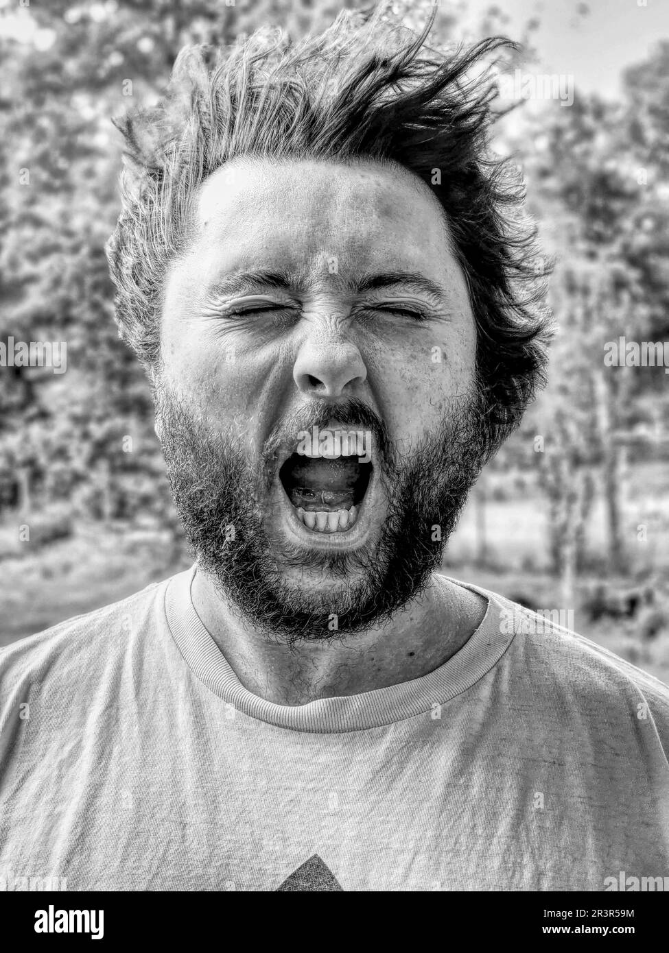 Black & White Photo of a man's face getting hit by wind, his eyes closed and mouth open Stock Photo