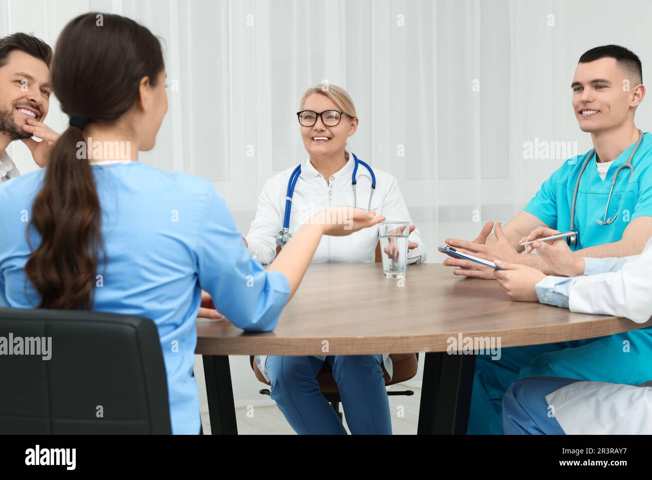 Medical conference. Team of doctors having discussion at wooden table ...