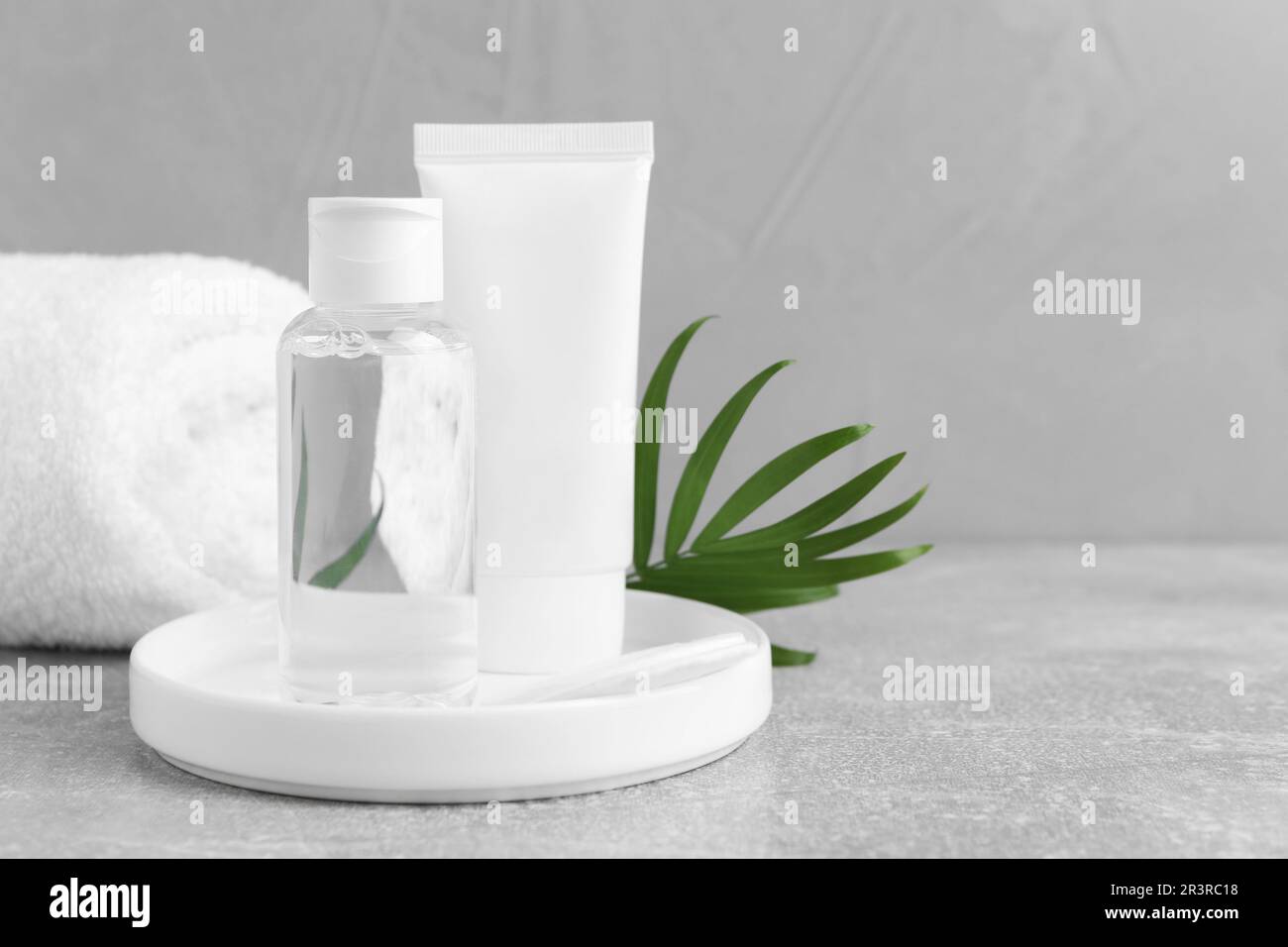 Micellar water and cream on grey table, space for text Stock Photo