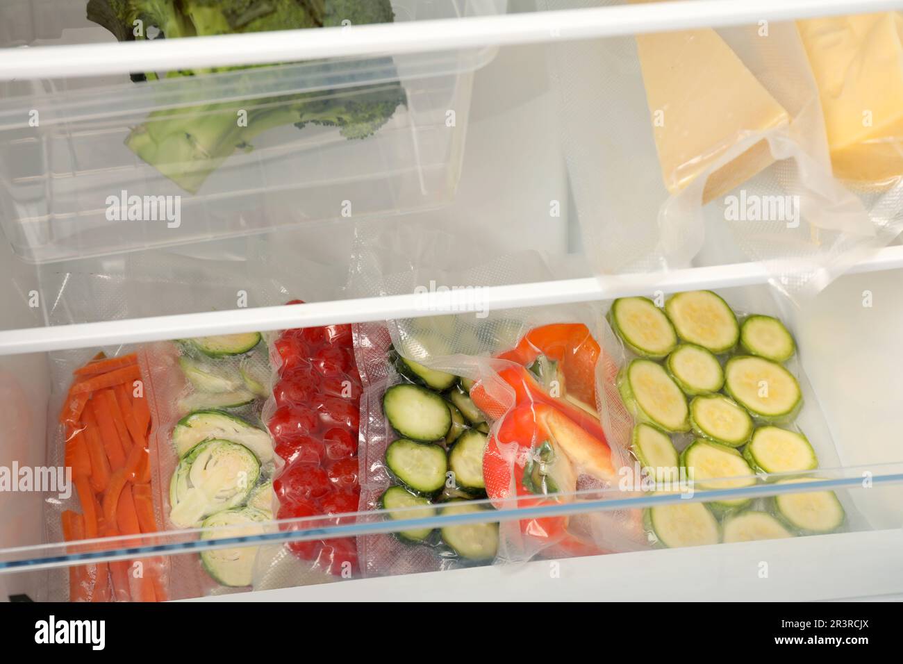 Vacuum bags with different vegetables in fridge. Food storage Stock Photo