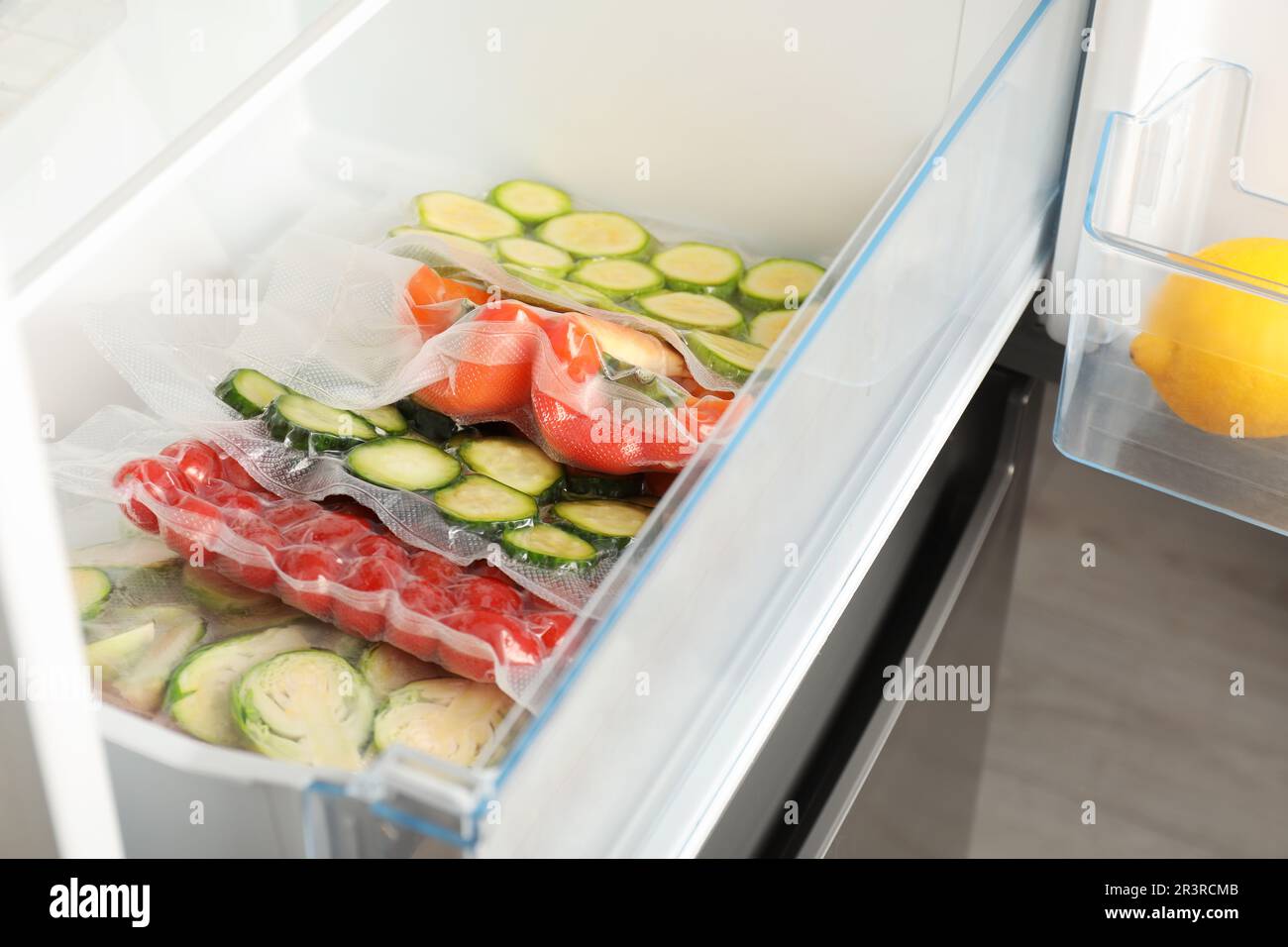 Vacuum bags with different vegetables in fridge. Food storage Stock Photo