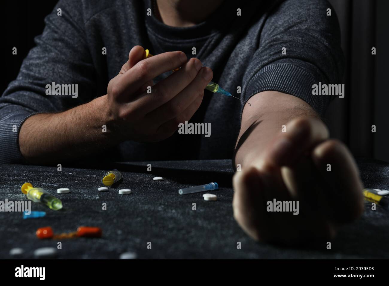 Addicted man taking drugs at black textured table, closeup Stock Photo