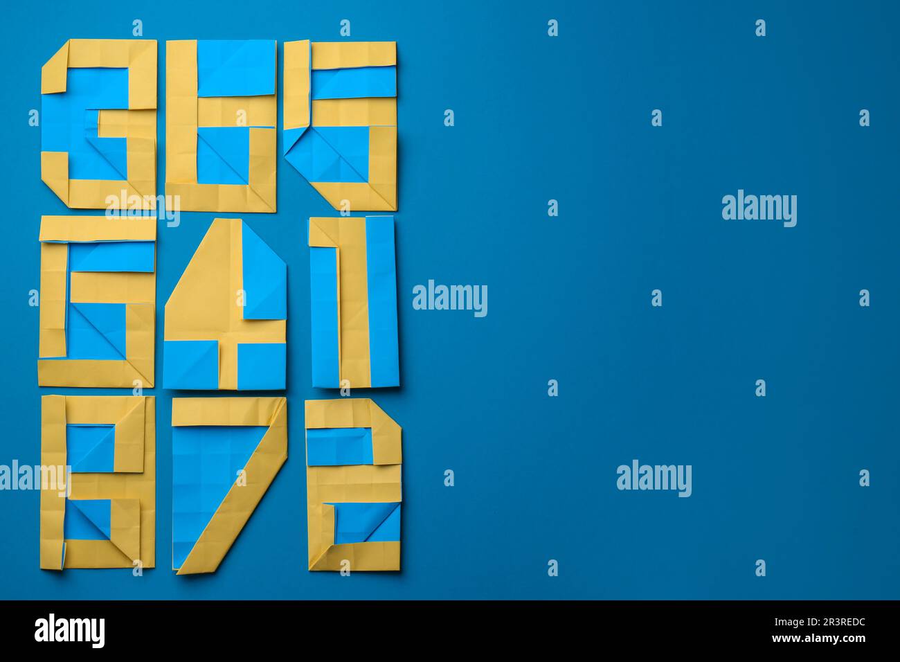 Different numbers made of paper on light blue background, flat lay ...