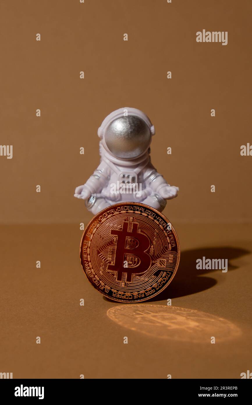 Plastic toy astronaut holding Bitcoin gold coin mining trading concept. BTC  golden money. Worldwide virtual internet Cryptocurrency or crypto digital  payment system. Concept of out of earth travel, private spaceman commercial  flights.